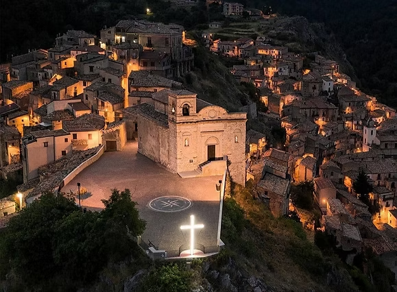 Abendlicher Blick auf einen beleuchteten Ort mit Kirche und schmalen Gassen